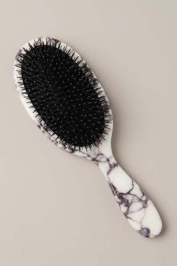 Hairbrush with a marbled handle on a beige background