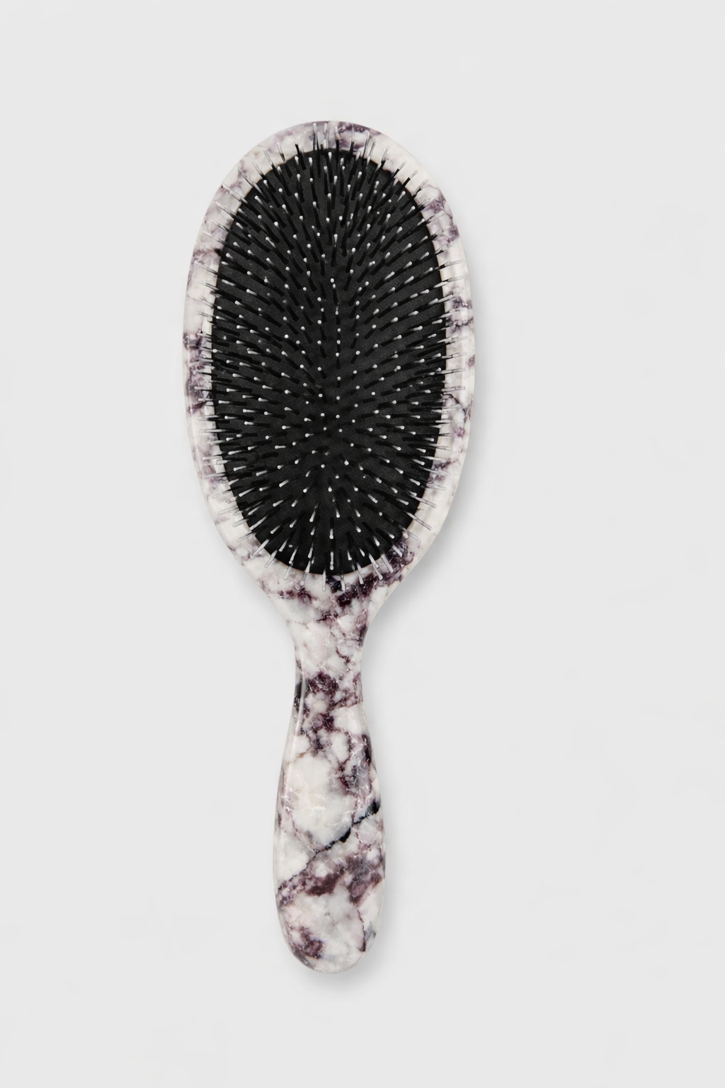 Hairbrush with marble handle on a light gray background