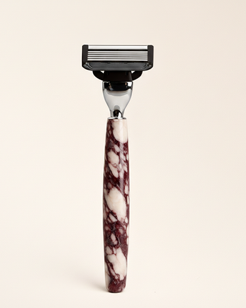 Shaving razor with a real marble handle on a beige background