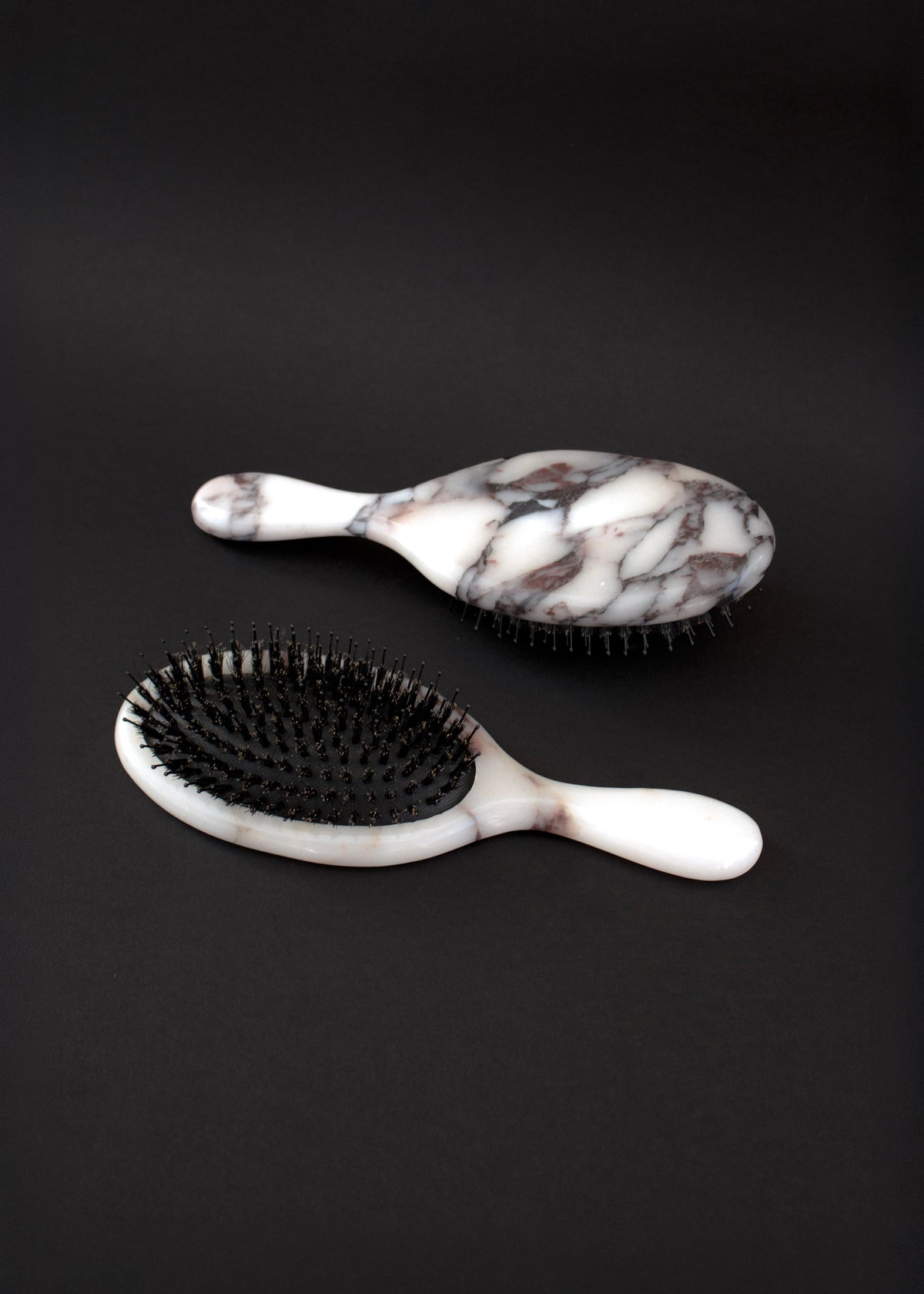 Two Marble Hairbrushes on black, the marble back and the black bristles