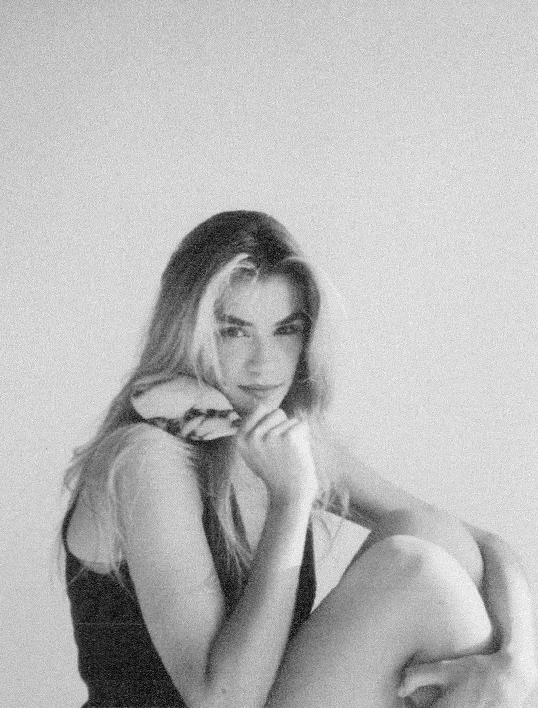 A woman seated, resting The Marble Hairbrush against her cheek, in black and white